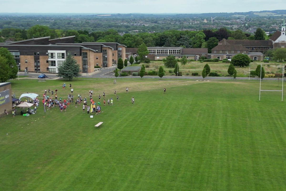 Aerial view of the start field at Harcourt Hill with runners gathering and Oxford on the horizon