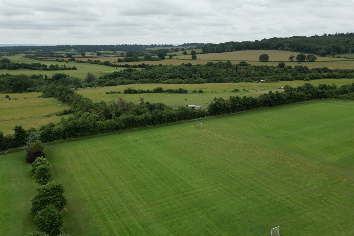 Hedged fields and woodland beyond the playing field, seen from the air