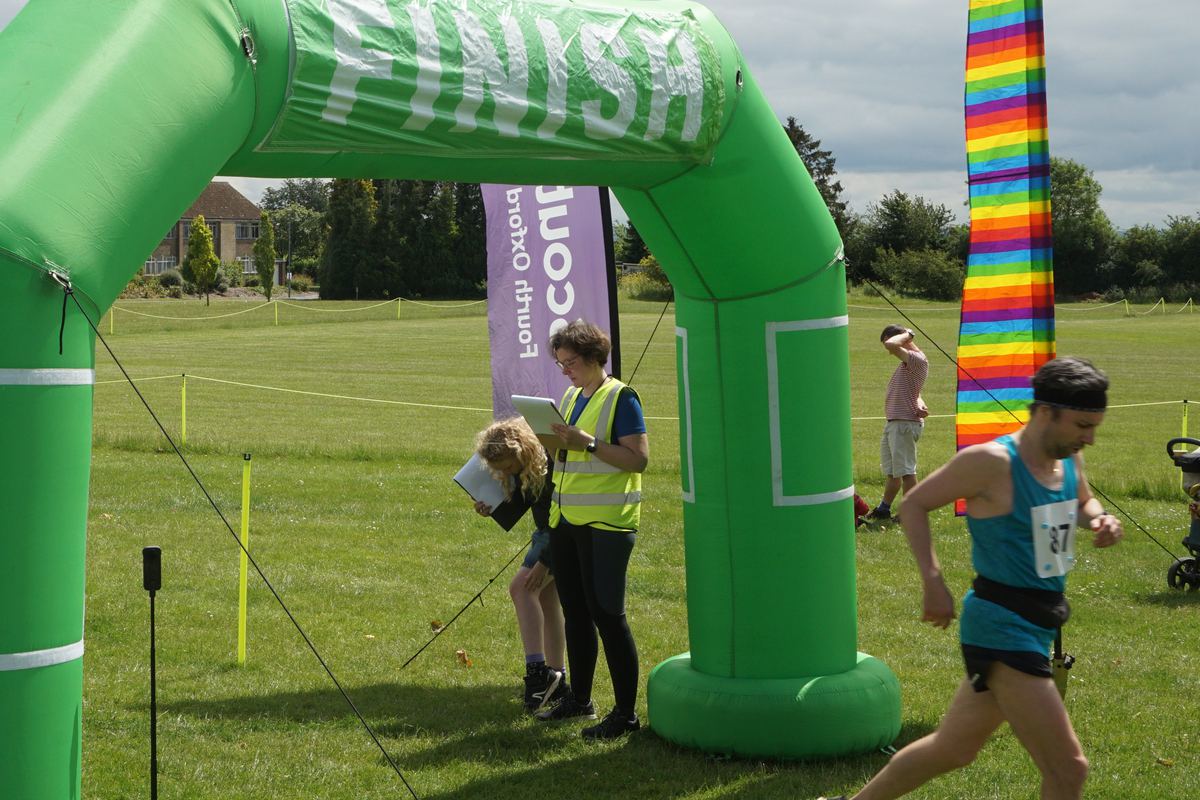 A runner striding out of the green inflatable finish arch