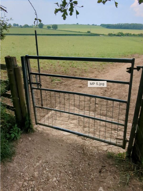 A metal gate with open fields beyond